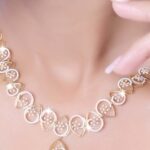 Close-up of a model wearing a stylish gold necklace against a soft background.